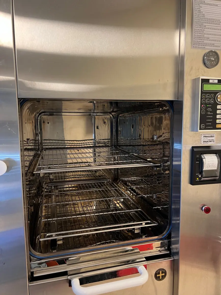 Open steam sterilizer chamber with racks